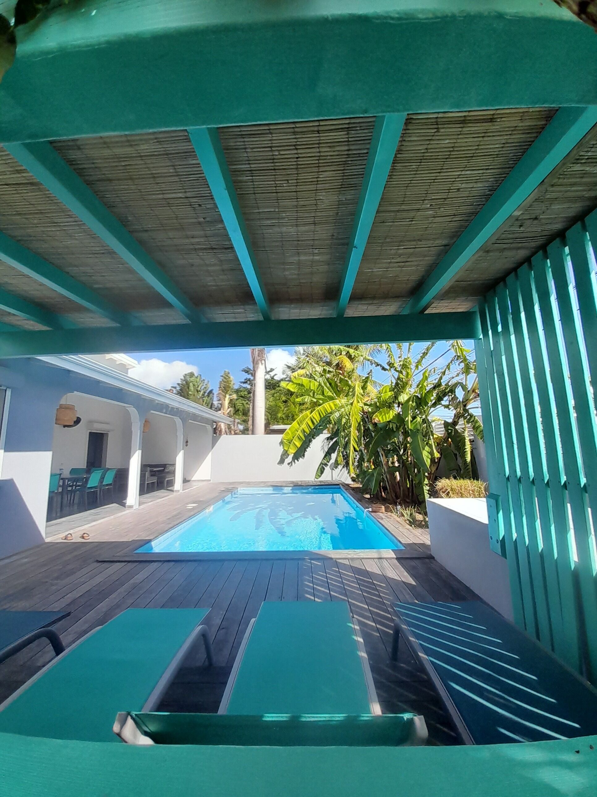 A pool area with a wooden deck and a covered section.