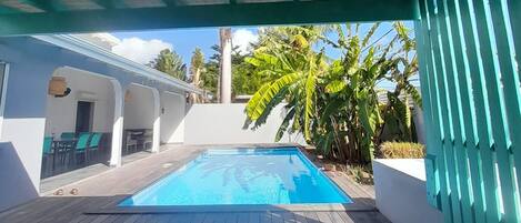 A pool area with a wooden deck and a covered section.