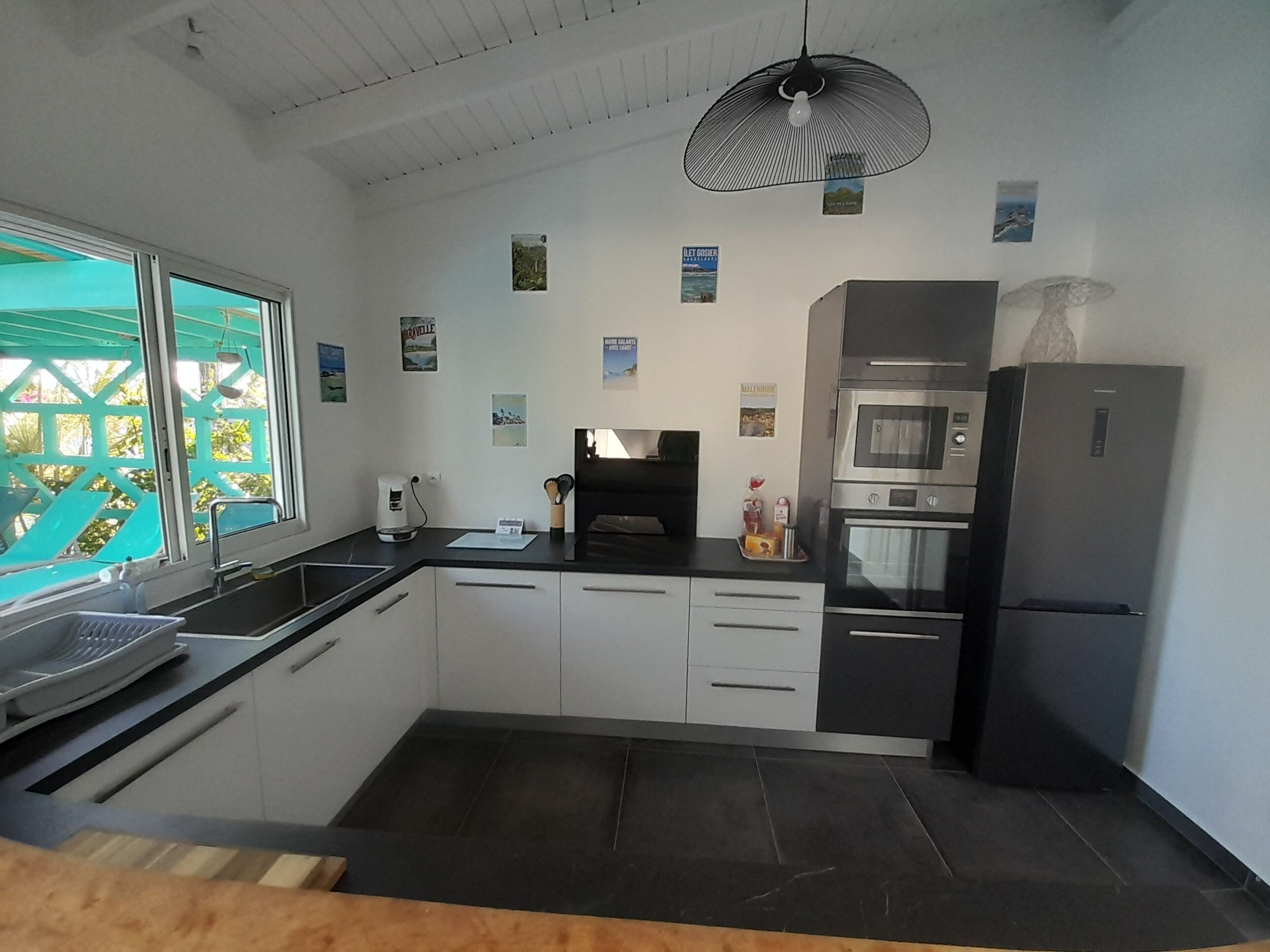 A modern kitchen with a black countertop, white cabinets, a built-in oven, and a refrigerator.
