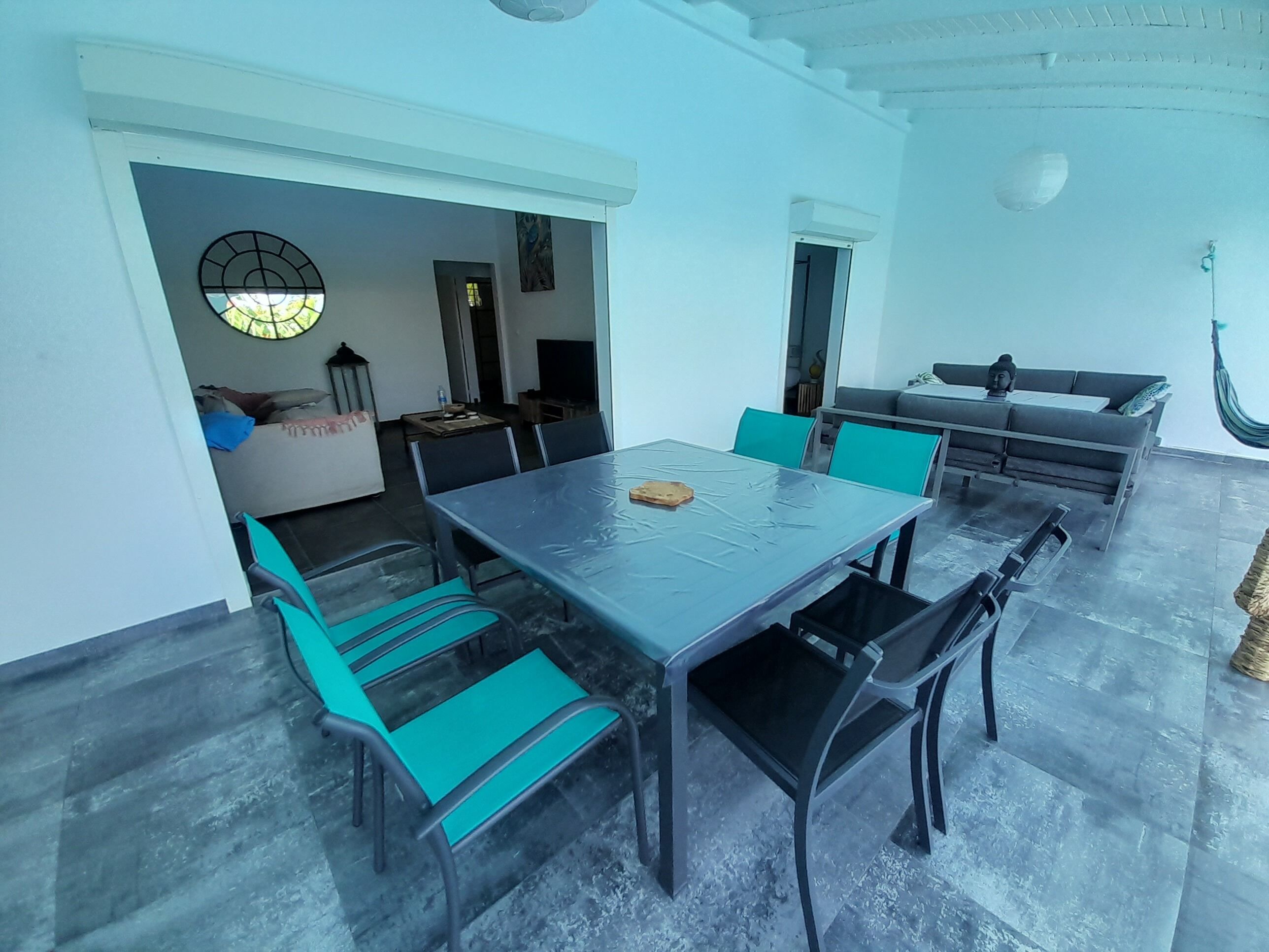 A spacious room with a large dining table surrounded by chairs, a sofa, and a hammock.