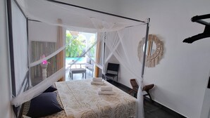 A room with a bed, a ceiling fan, a table, and a bench.