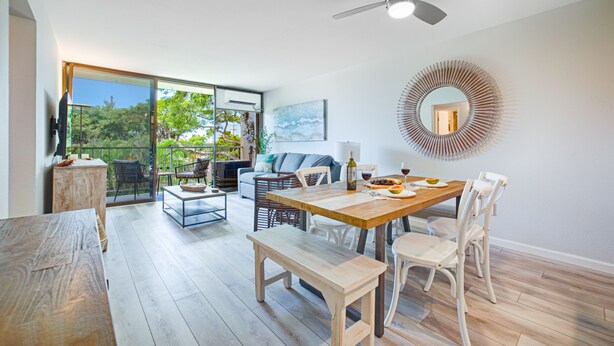 A spacious room with a dining table, chairs, a sofa, and a ceiling fan. - Ocean view, fully remodeled, 2nd floor, few steps away from the best beaches (Kihei)