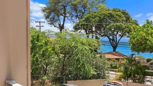 A coastal view with trees and a building in the background. - Ocean view, fully remodeled, 2nd floor, few steps away from the best beaches (Kihei)