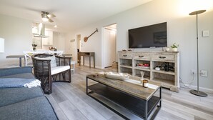 A modern living room with a sofa, coffee table, and a TV on a wooden cabinet. - Ocean view, fully remodeled, 2nd floor, few steps away from the best beaches (Kihei)