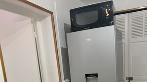 Una cocina equipada con refrigerador, microondas, dispensador de agua y tetera.
