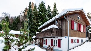 A two-story wooden chalet with red shutters, a balcony, and a snow-covered roof. - Cozy Apartmentbergpanoramasichtfree Parking (Flums)