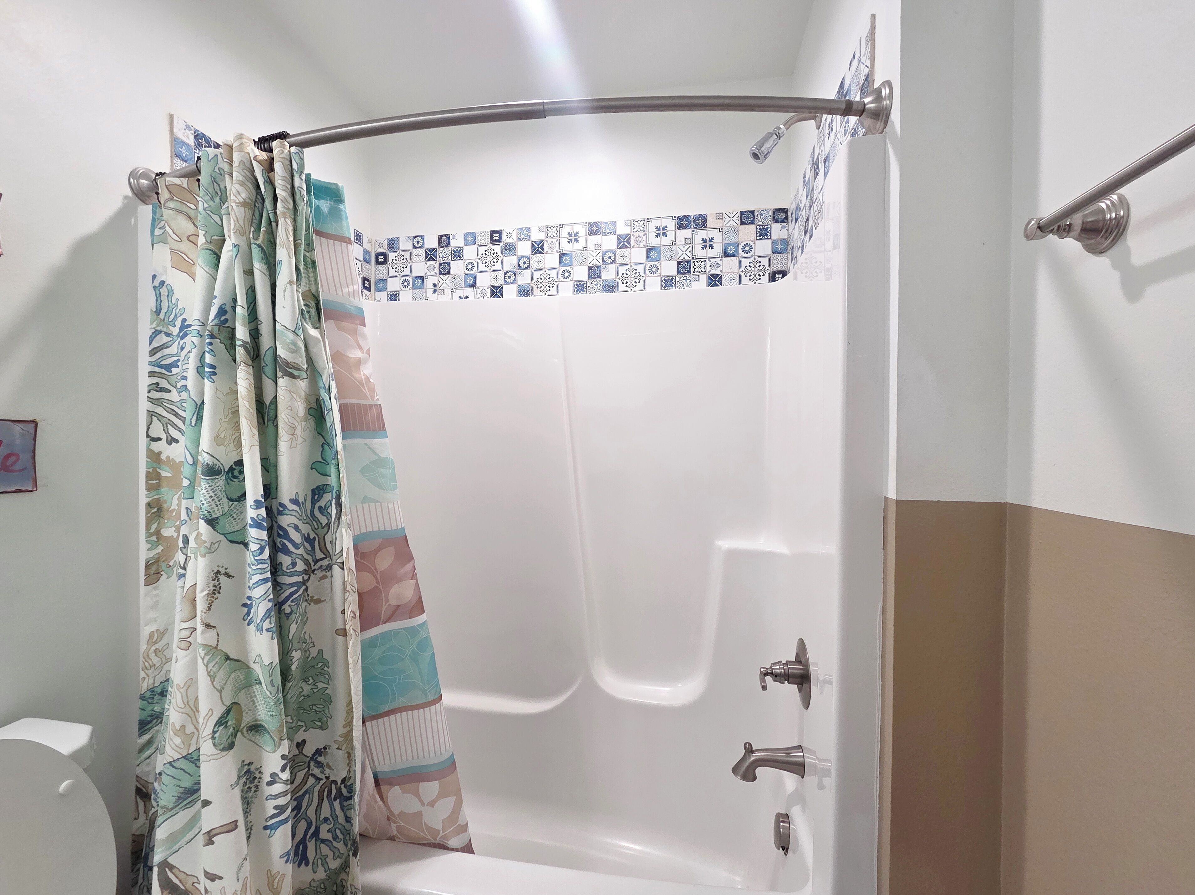 A bathroom with a shower curtain, a bathtub, and a tiled shower area.