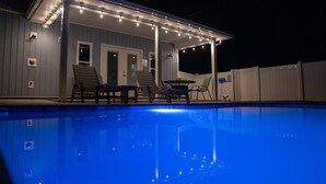 Un espace extérieur abrité comprenant une piscine, des chaises et une table.