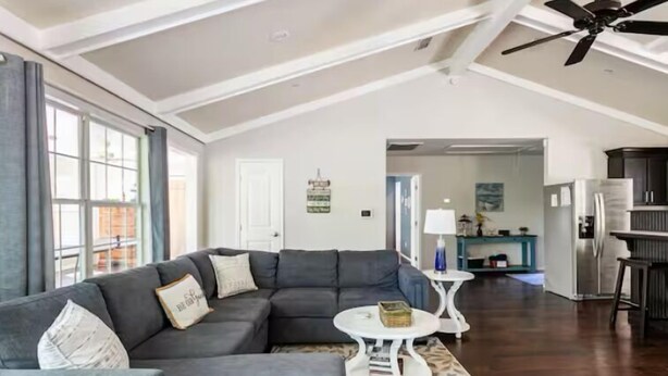 A modern living room with a sectional sofa, a round coffee table, and a ceiling fan.