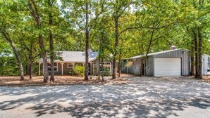 A residential property with a covered porch, a garage, and a gravel driveway.