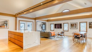 A spacious living area with a wooden ceiling, a marble island, a sofa, and a dining table with chairs. - The Penthouse, Downtown Lenox by Evergreen Home (Lenox)