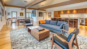A spacious living room with a sofa, coffee table, and chairs, a dining area with a table and chairs, and a kitchen with modern appliances and wooden cabinets. - The Penthouse, Downtown Lenox by Evergreen Home (Lenox)