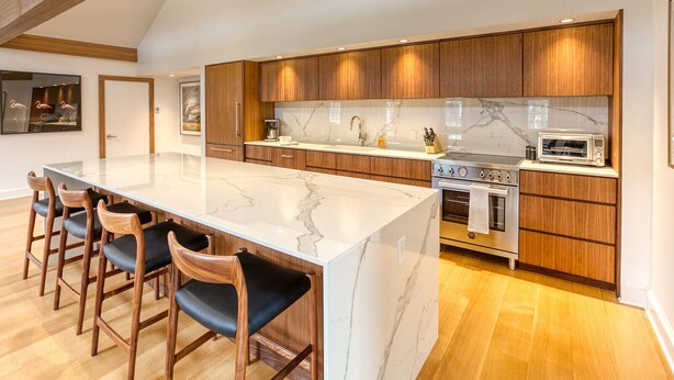 A modern kitchen with a large island, wooden cabinets, and a marble countertop. - The Penthouse, Downtown Lenox by Evergreen Home (Lenox)
