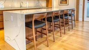 A kitchen with a marble island and wooden bar stools. - The Penthouse, Downtown Lenox by Evergreen Home (Lenox)