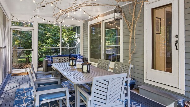 A covered patio with a wooden table and chairs, string lights, and a bench. - Berkshires Colonial on 2 Acres by Evergreen Home (Pittsfield)