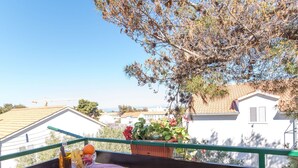A balcony with a table set for two, overlooking a residential area with houses and a clear sky. - Apartments Pinija - Standard Two Bedroom Apartment With Balcony - (Supetar)