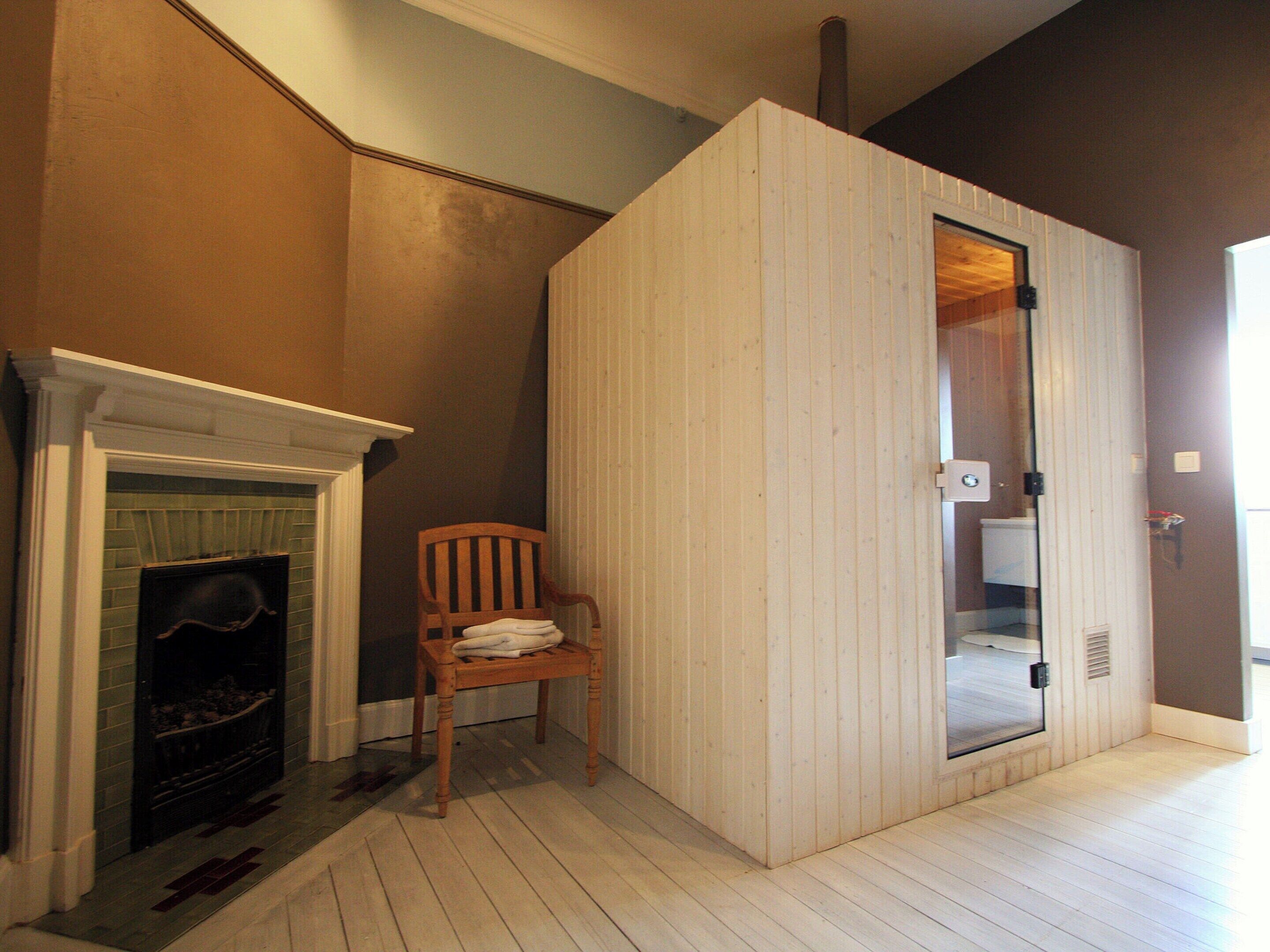 A room with a fireplace, a wooden chair, and a door leading to a bathroom.
