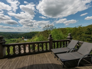 A wooden deck with a stone balustrade overlooking a scenic landscape with trees and a lake. - Castle in Spa With Lake View & Heated Pool (Jalhay)