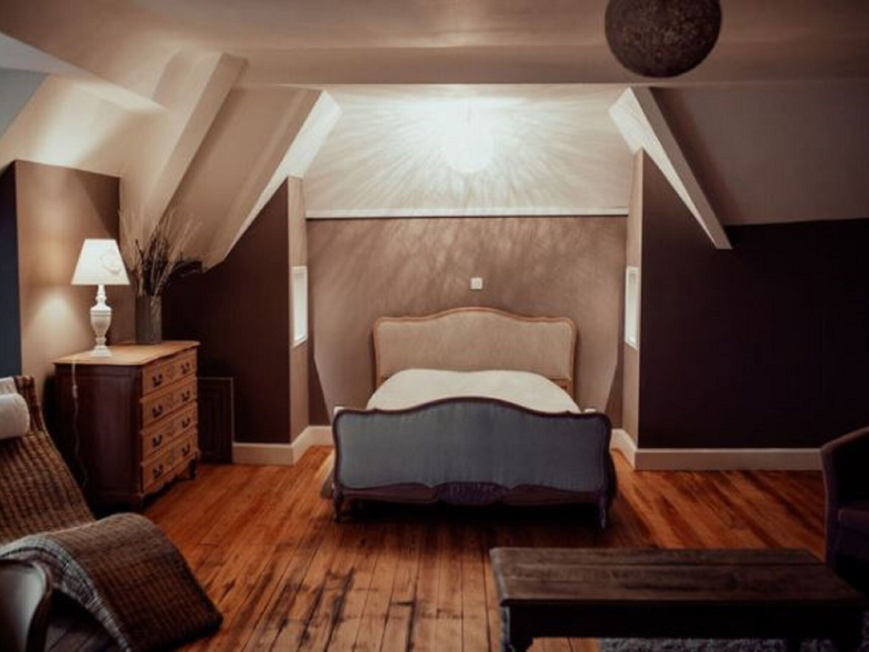A bedroom with a bed, a dresser, a lamp, and a chair.