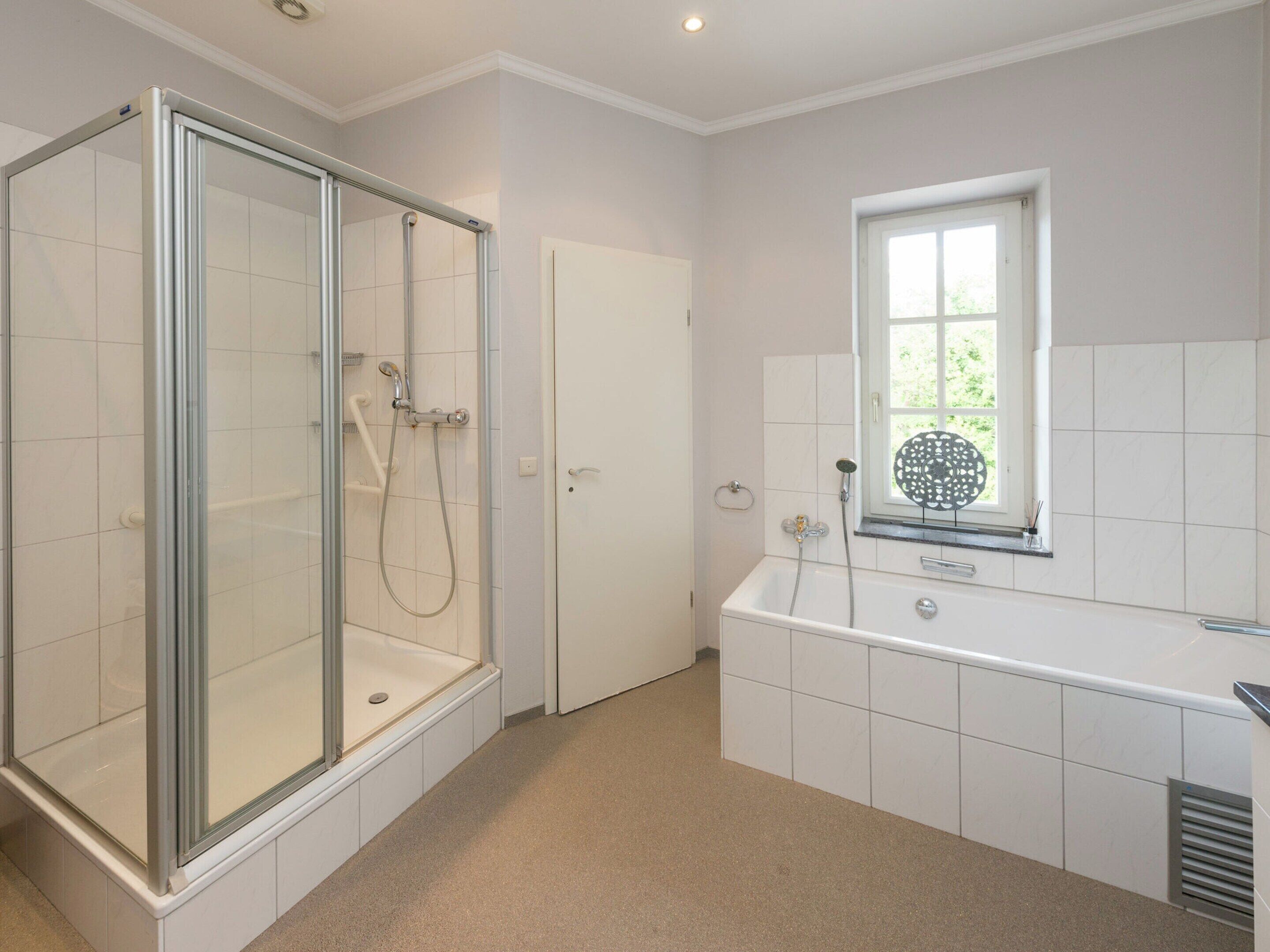 A modern bathroom with a glass-enclosed shower, a bathtub, and a window providing natural light.