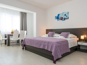 A modern hotel room with a large bed, a desk with chairs, and a dining table. - Villa Kabalero - Four-bedroom Villa With Private Pool (Konavle)