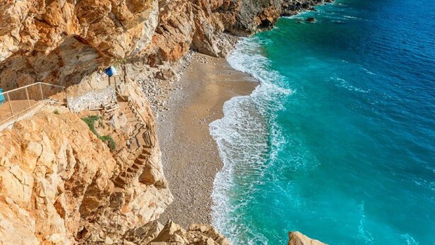 Eine Küstenklippe mit einem felsigen Strand und einem klaren, blauen Meer.