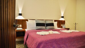 Ein Hotelzimmer mit einem großen Bett, zwei Nachttischlampen, einem Holznachttisch und einem gemusterten Teppich.