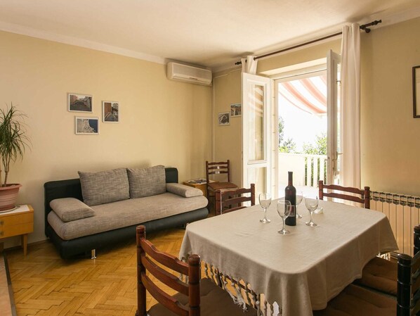 A dining area with a table set for four, a sofa, and a potted plant.