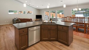 A spacious kitchen with a central island, wooden cabinets, and a dishwasher. - Manzanita - Hot Tub, Canal Front, Amazing Location! (Bend)