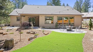 A two-story house with a patio, outdoor seating, and a well-maintained lawn. - Manzanita - Hot Tub, Canal Front, Amazing Location! (Bend)