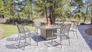 A patio with a fire pit table and chairs, surrounded by trees. - Manzanita - Hot Tub, Canal Front, Amazing Location! (Bend)