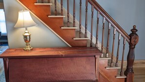 Un piano de cola, una lámpara y una escalera de madera con ventilador de techo.