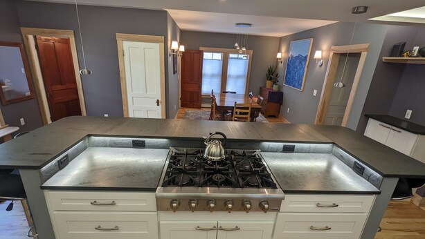 Una cocina moderna con una isla central, electrodomésticos de acero inoxidable y armarios blancos.