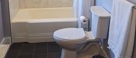 A bathroom with a bathtub, toilet, and a shower curtain.
