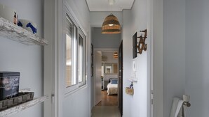 A narrow hallway with a bed in the background, a wicker pendant light, and a shelf with various items. - AN4-Loft- Cozy Loft with private terrace in the he (Athens)
