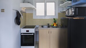 Una cocina compacta con estufa, horno, microondas y un frutero sobre la encimera.