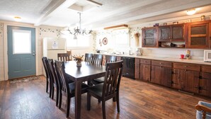 A kitchen with wooden cabinets, a dining table with chairs, and a refrigerator. - Quaint 3-bedroom cottage in Nashville, shopping, and dining! Pet-friendly! (Nashville)