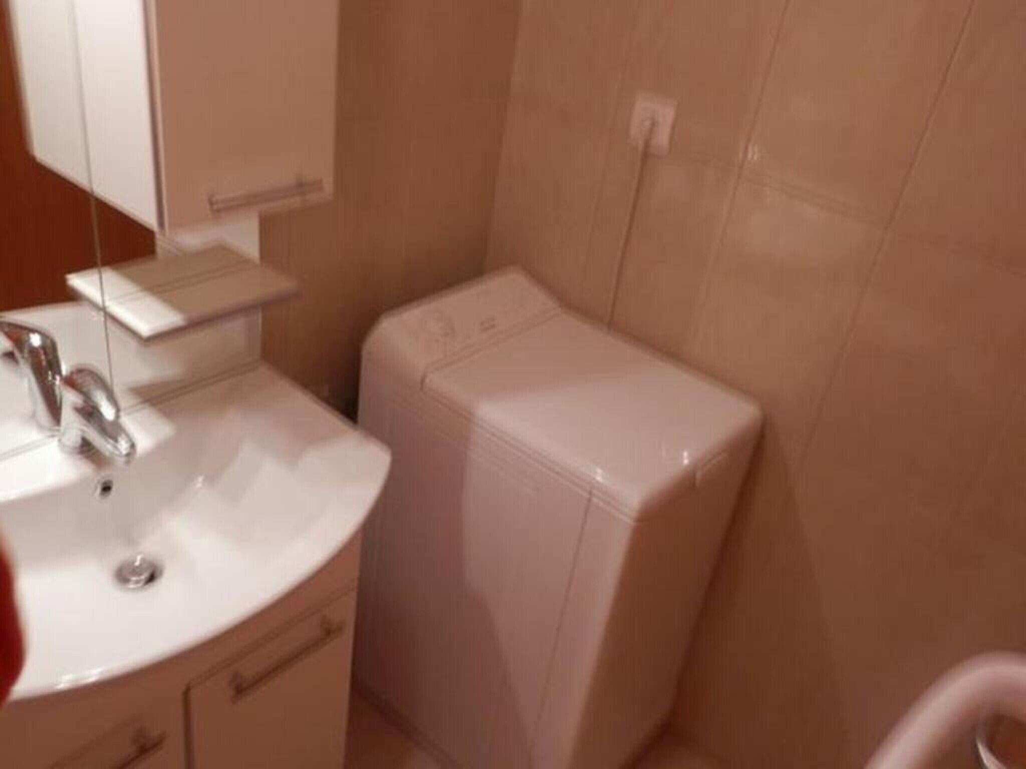 Ein Badezimmer mit einem weißen Waschbecken, einem Spiegel und einer kleinen weißen Kommode.