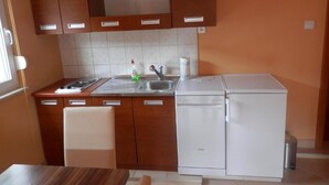 A compact kitchen with wooden cabinets, a white refrigerator, and a sink.
