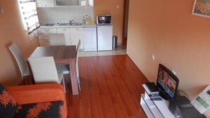 A compact living space with a kitchenette, a dining area, and a seating area with a TV. - Apartments St Rialto - Comfort One-Bedroom Apartment with Balcony and Sea View (Jelsa)