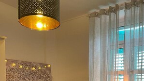 A bedroom with a bed, a hanging light fixture, a window with curtains, and a wall-mounted picture. - Apartment Fresh Start- One Bedroom Apartment (Zadar)