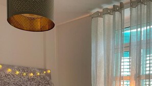 A bedroom with a bed, a wall-mounted light fixture, and a window with curtains. - Apartment Fresh Start- One Bedroom Apartment (Zadar)