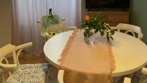 A dining area with a round table, chairs, a vase with flowers, and a television on a cabinet. - Apartment Fresh Start- One Bedroom Apartment (Zadar)
