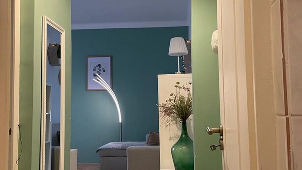 A hallway leading to a living room with a sofa, a lamp, and a vase on a white cabinet. - Apartment Fresh Start- One Bedroom Apartment (Zadar)