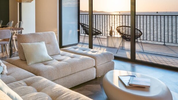 A modern living room with a large sofa, a round coffee table, and two black chairs. A large window offers a view of the sea. - Cezon Island - Luxury duplex with magnificent sea (Landéda)