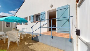 A building with a staircase, outdoor seating, and blue shutters.