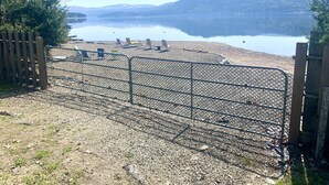 A gravel path leading to a fenced beach area with lounge chairs and a lake in the background. - Sunnyside Lakehouse - Semi-waterfront Shuswap Accommodation (Celista)