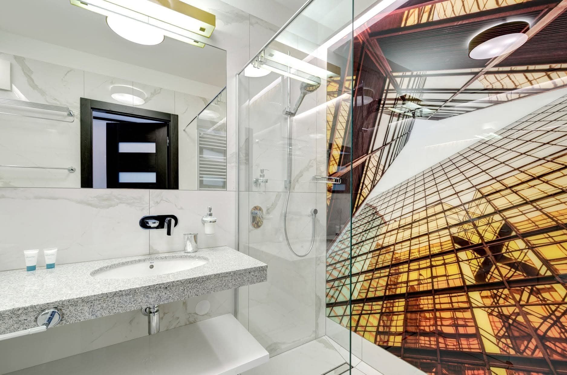 Une salle de bain moderne avec un lavabo en marbre, un miroir et une douche séparée par des parois en verre.