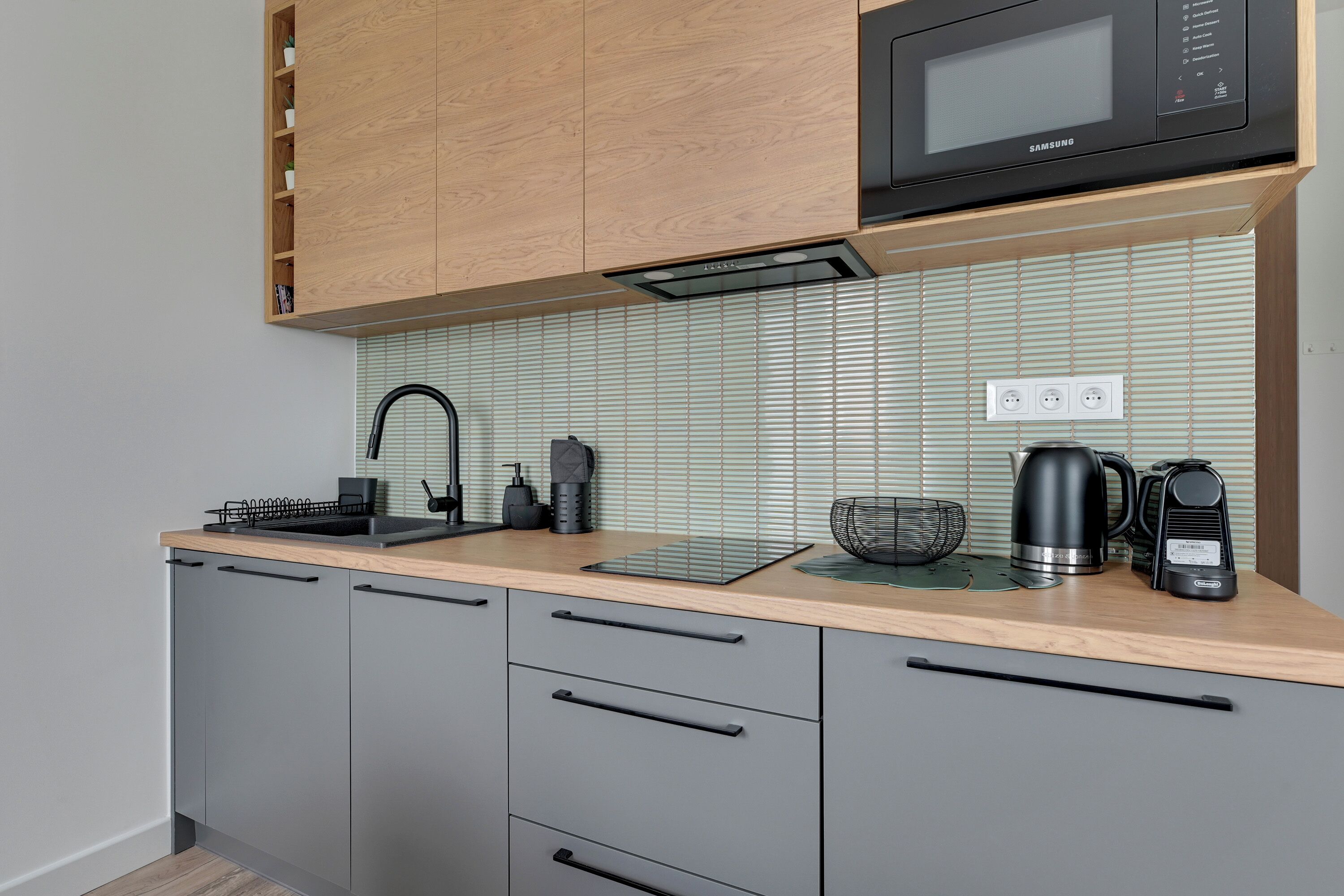 A modern kitchen with a microwave, kettle, and coffee maker on the counter.