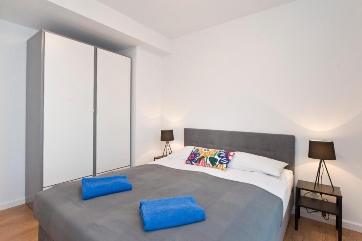 A modern bedroom with a bed, two bedside tables, a wardrobe, and a nightstand.